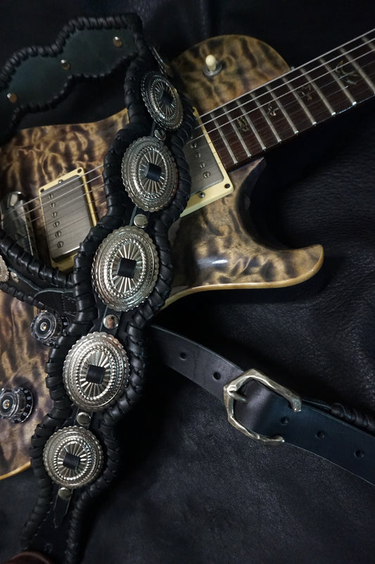 BLACK RAIDEN "黒雷電" handmade leather guitar strap worn on electric guitar on stage, black cowhide with silver conchos